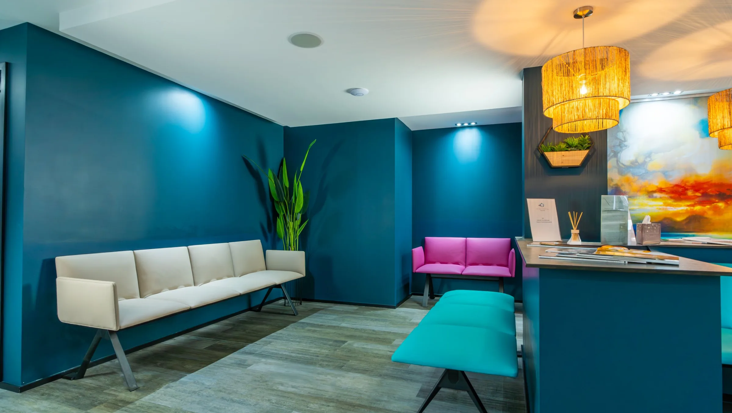 Waiting area at hobe dental clinic with a cream bench, pink chairs and deep blue walls.